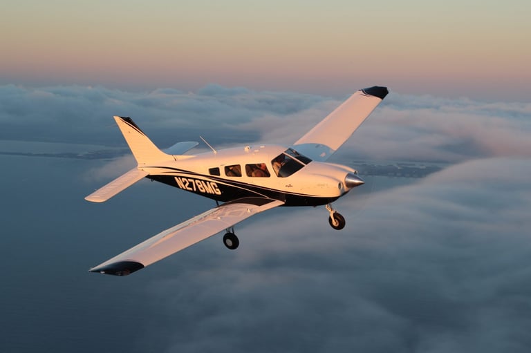 Small single-engine aircraft flying above clouds during sunset