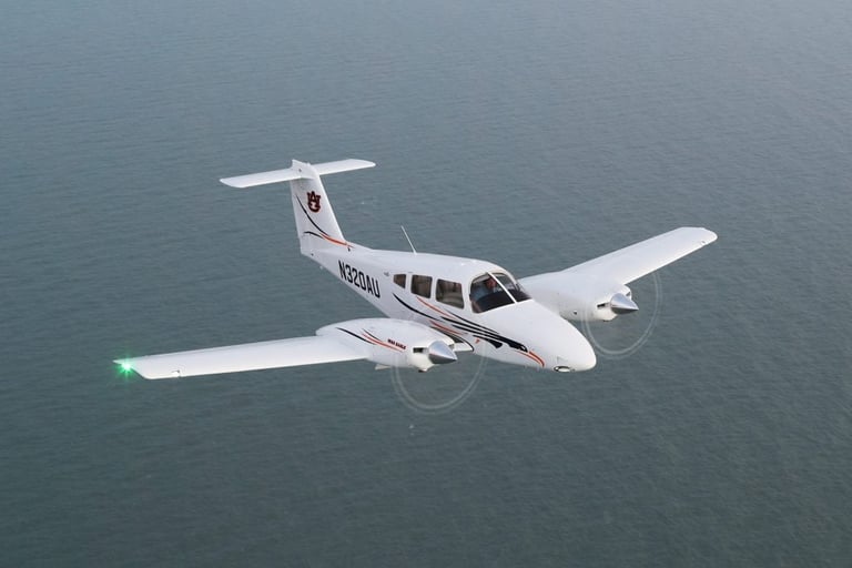 Overhead aerial view of a white twin-engine aircraft flying over blue ocean water