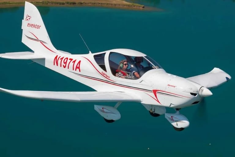 Aerial view of a white and red small aircraft with registration N1971A flying over turquoise water